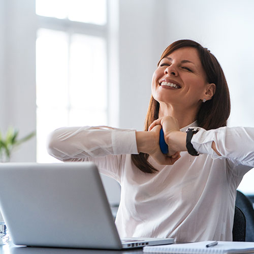 happy debt relief client smiling and sitting at her desk